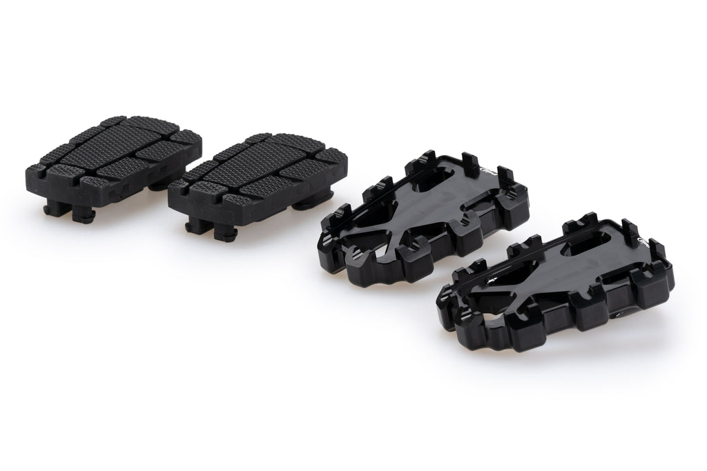 Black PUIG Enduro 2.0 footpegs for motorcycle foot controls, showing textured surfaces and mounting points.