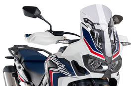 Clear PUIG racing windscreen for motorcycle, aerodynamic windshield with mounting edges and reflective surface.