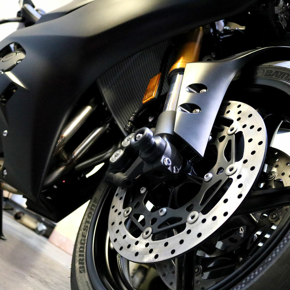 Black Shogun Industries front axle sliders mounted on motorcycle body, designed for protection and style.