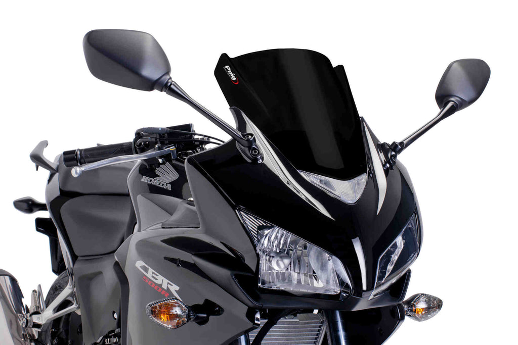Black PUIG racing windscreen for motorcycle, showing sleek aerodynamic design and mounting hardware for high-performance riding.