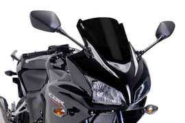 Black PUIG racing windscreen for motorcycle, showing sleek aerodynamic design and mounting hardware for high-performance riding.