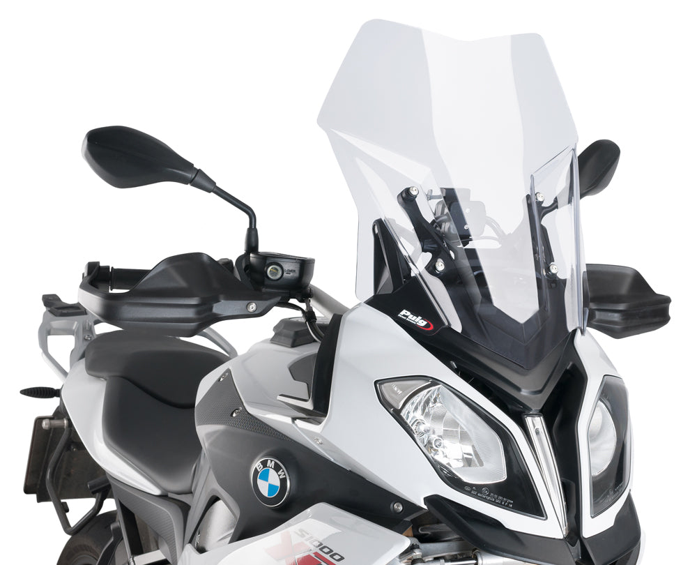 Clear PUIG touring windscreen for motorcycle, showing its curved, transparent design and mounting edges.