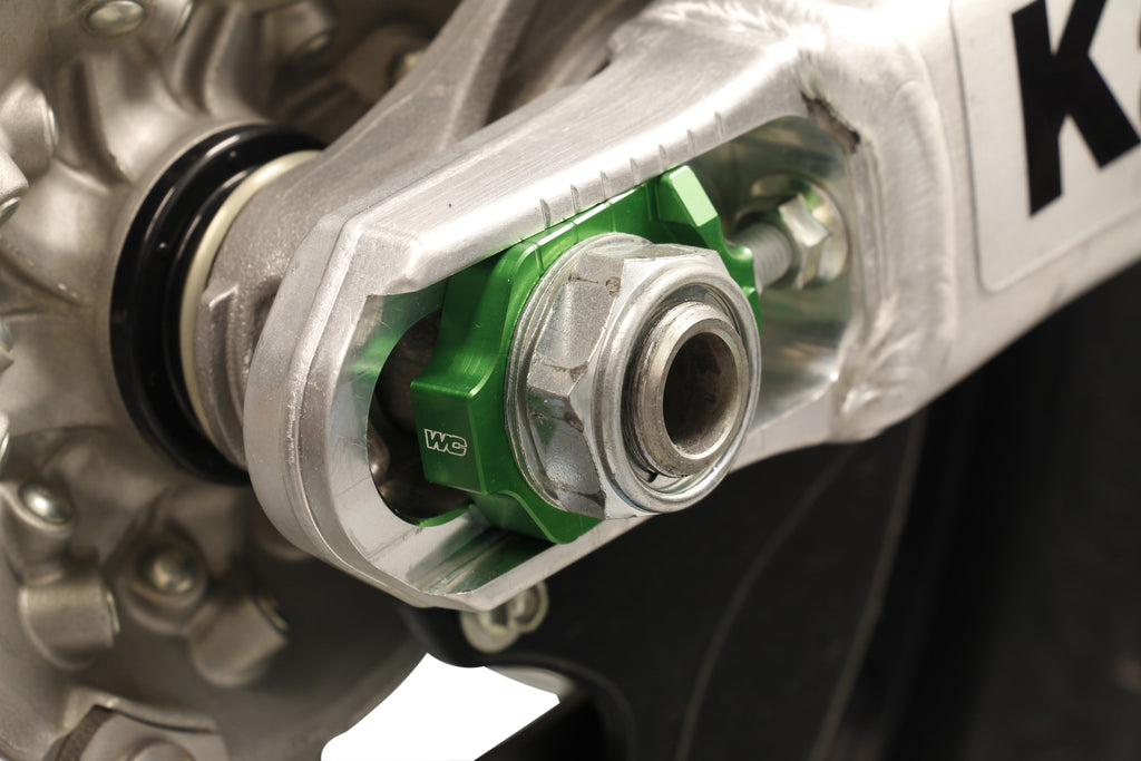 WORKS Axle Blocks Elite for Kaw/Suz Green drive axle, durable motorcycle wheel stabilizers with bright green finish.