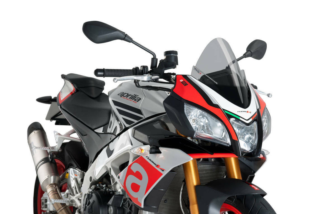 PUIG racing smoke windshield for motorcycle, clear with dark smoke tint, aerodynamic design, mounted on bike in a racing setting.
