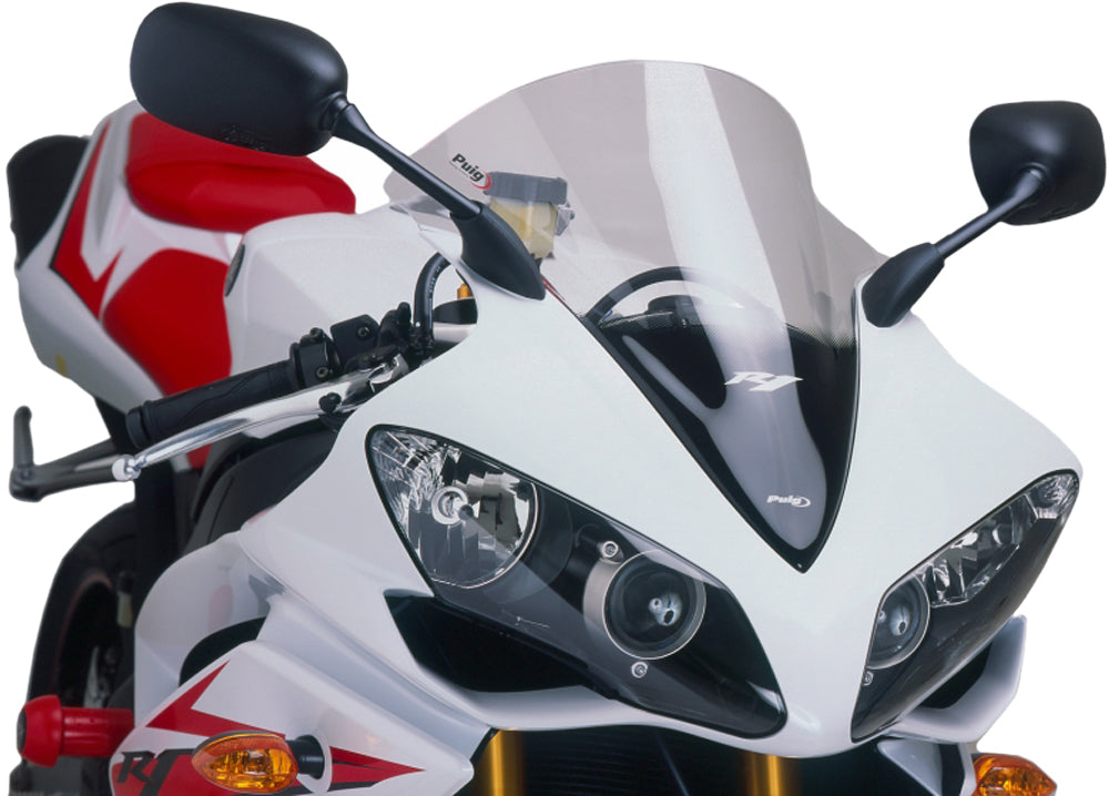 Clear PUIG racing windscreen for motorcycle, aerodynamic windshield with mounting brackets, designed for enhanced racing performance.