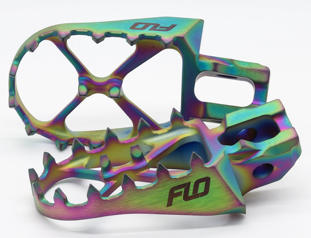 Flo Motorsports titanium foot pegs for Jet Fuel Gas, Husqvarna, and KTM dirt bikes, shown with textured surface and mounting hardware.