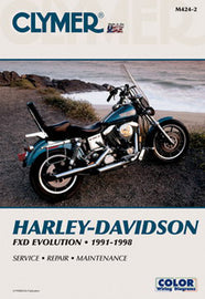 Clymer Harley Dyna-Gld 27-M424 repair manual with tools, showing the cover and included contents on a workspace surface.