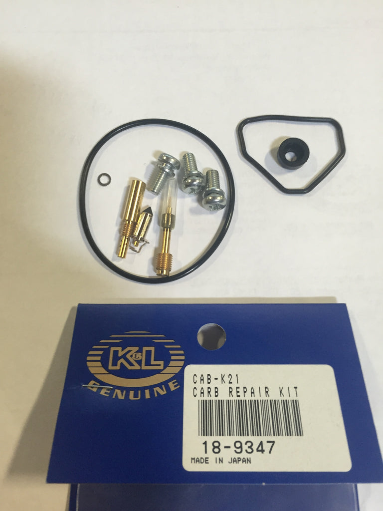 K&L Carb Repair Kit with various small components and tools for carburetor maintenance, arranged on a white surface.