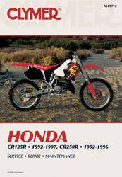 Clymer repair manual for Honda CR125 and CR250R motorcycles, open pages showing detailed maintenance instructions and diagrams.