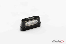 Black aluminum Puig license plate light with sleek design, showcasing a close-up of the illuminated light on a vehicle.
