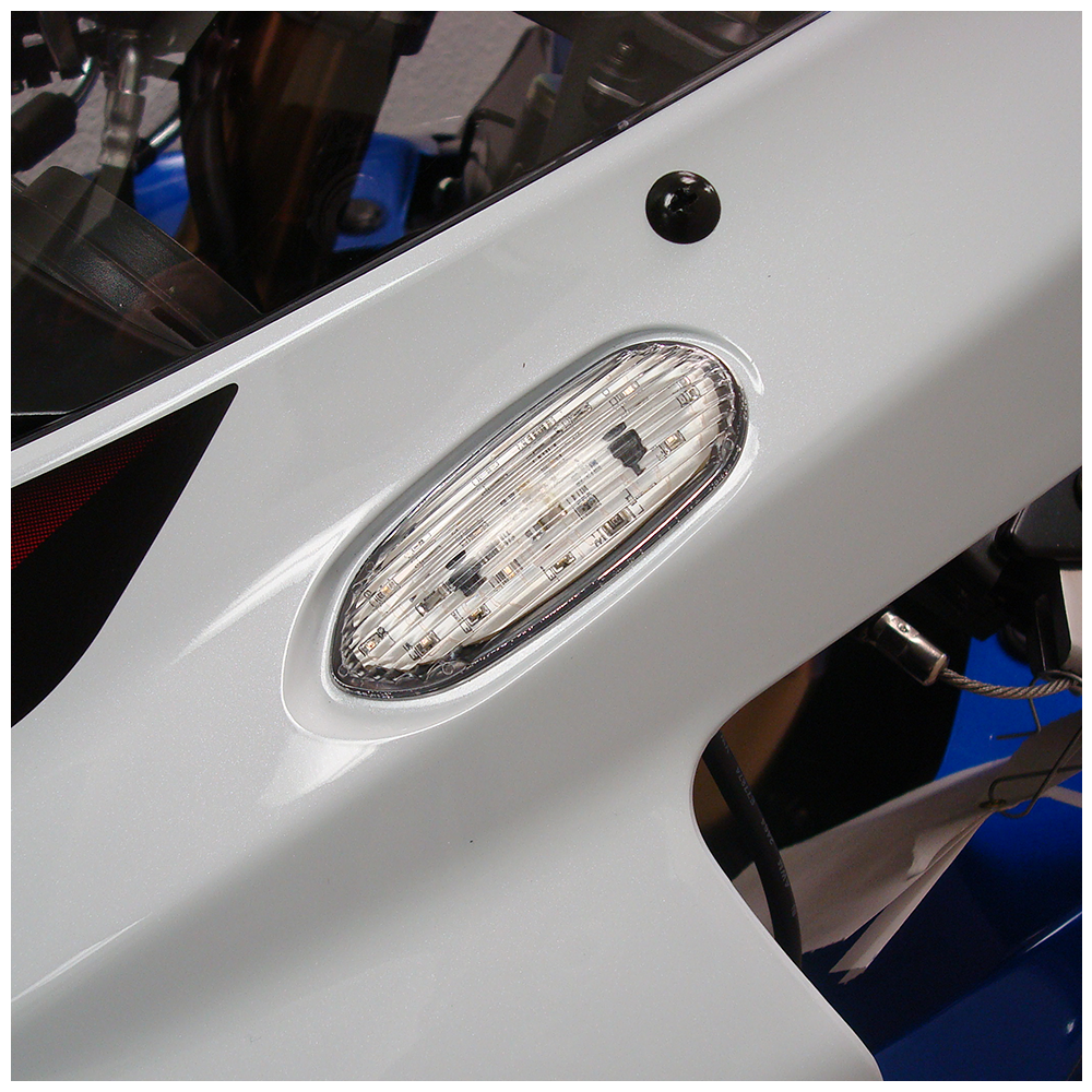 Clear flush mount signal light by Hotbodies Racing, designed for motorcycle illumination, with a sleek, compact appearance.